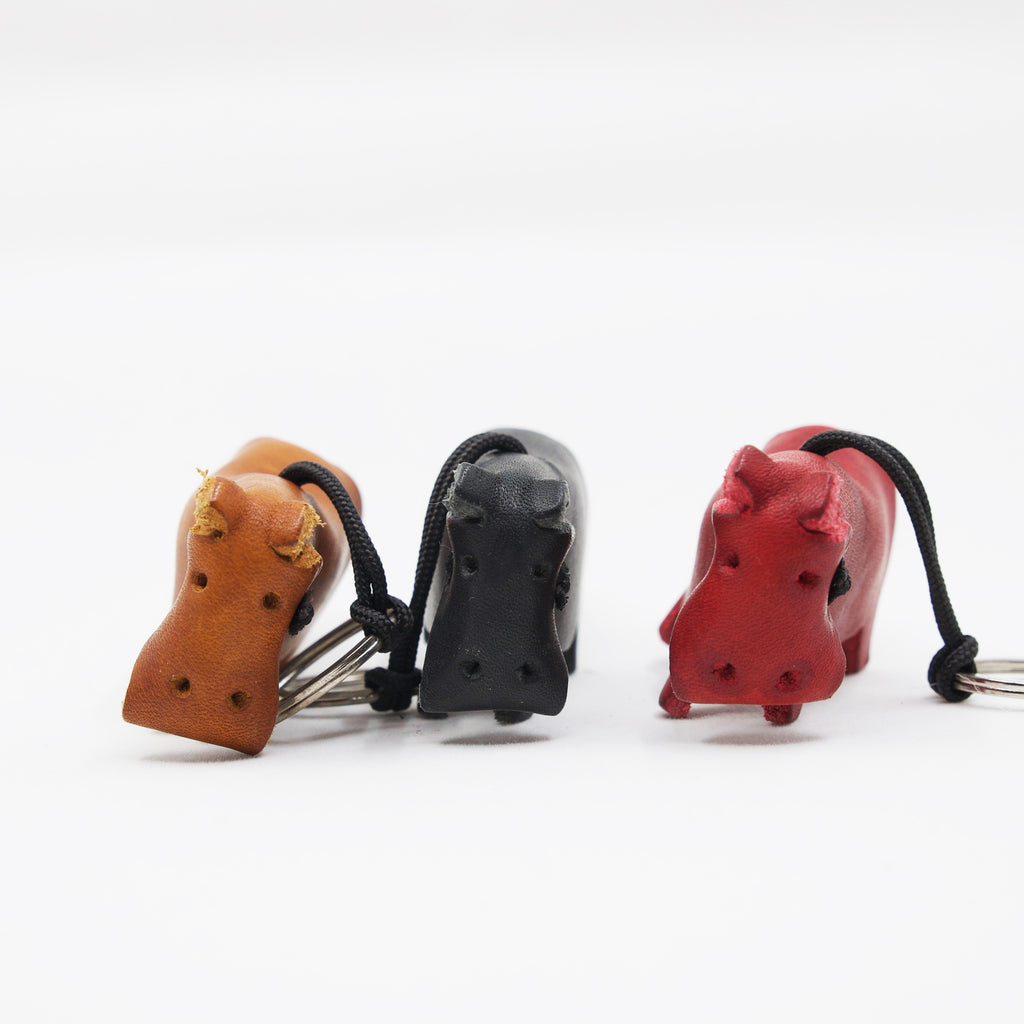 trio of artisan crafted hand stitched hippo keychains in tan, black and red leather. 