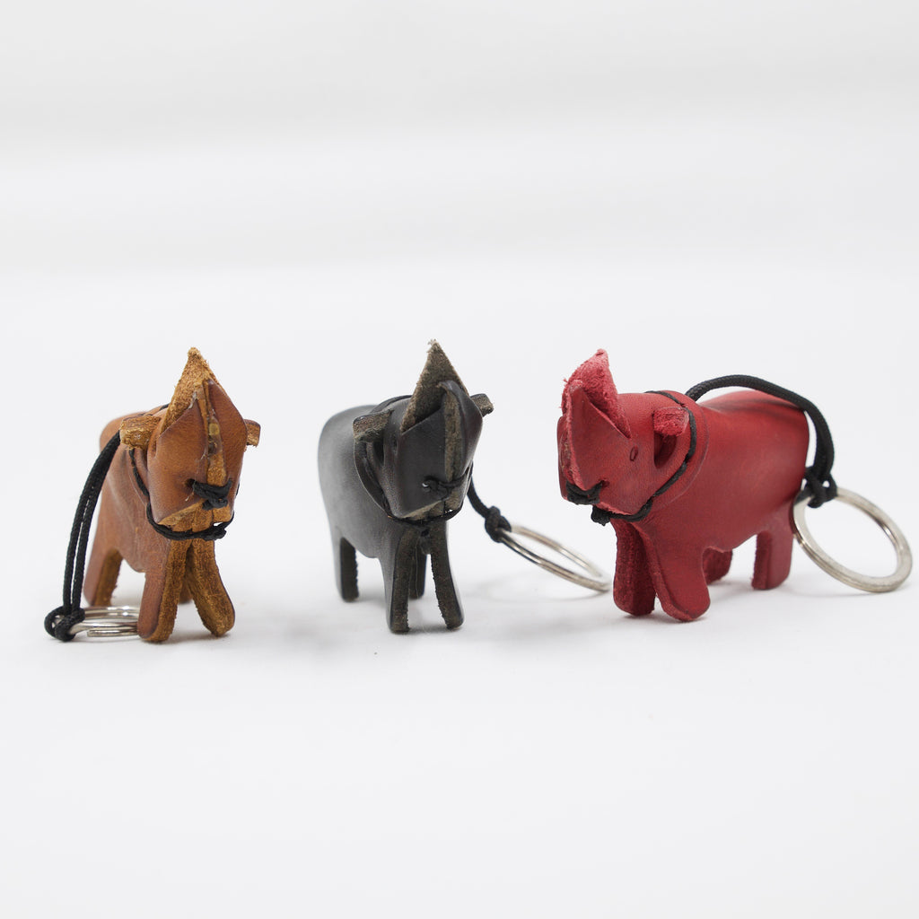 trio of artisan crafted hand stitched rhino keychains in tan, black and red leather. 