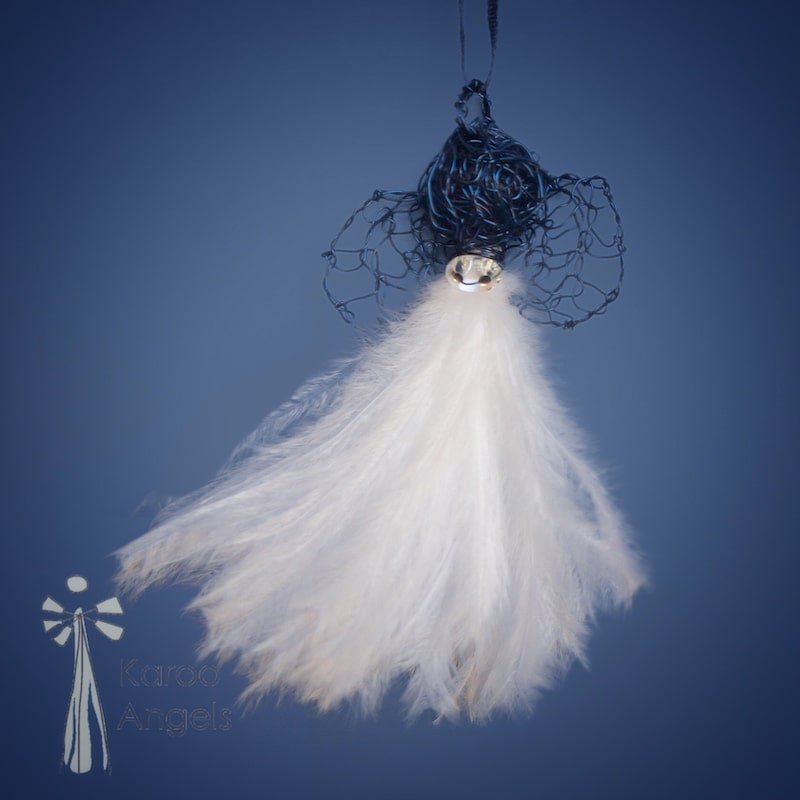 Tiny and delicate Karoo Angels Juweel Angel Pendant. Made of crocheted midnight blue coloured coated copper wire adorned with a small preciosia crystal bead and white ostrich feathers. It hangs off a silk tie matching the colour of the wire.  Size 3.5cm