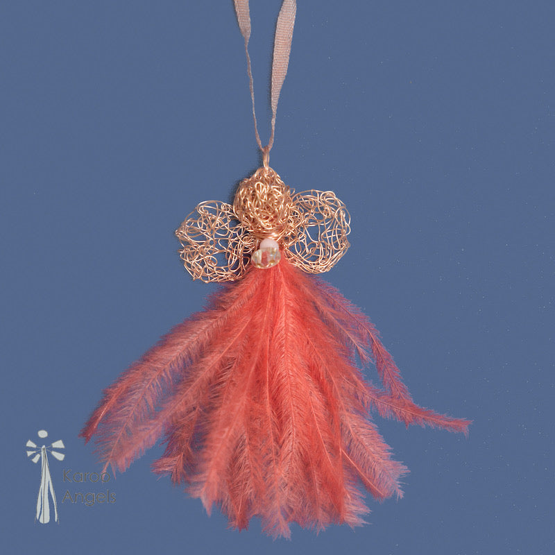 Tiny and delicate Karoo Angels Juweel Angel Pendant. Made of crocheted rose gold coloured coated copper wire adorned with a small preciosia crystal bead and coral ostrich feathers. It hangs off a silk tie matching the colour of the wire.  Size 3.5cm