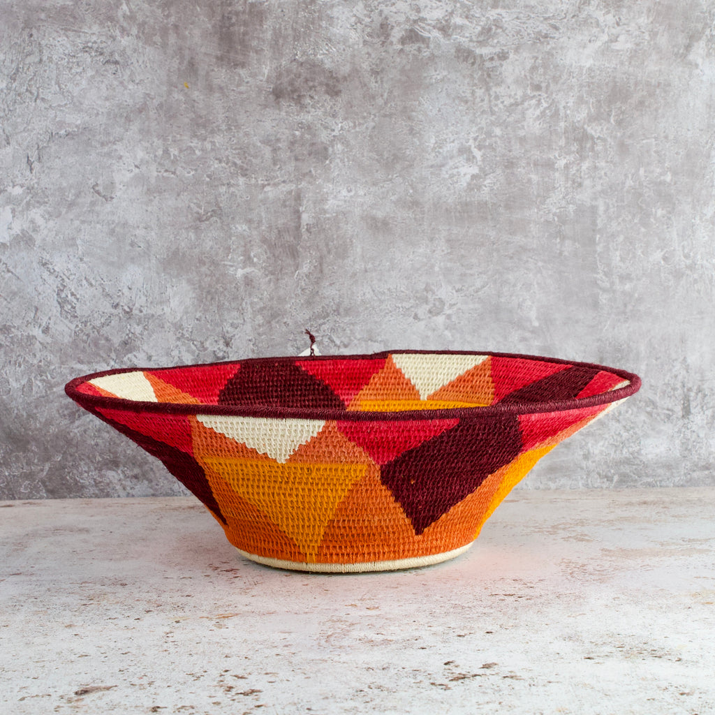 side view of large hand woven sisal basket. Sundial pattern. summer of love mixed colours of cream, mango,coral, fuscia, aubergine