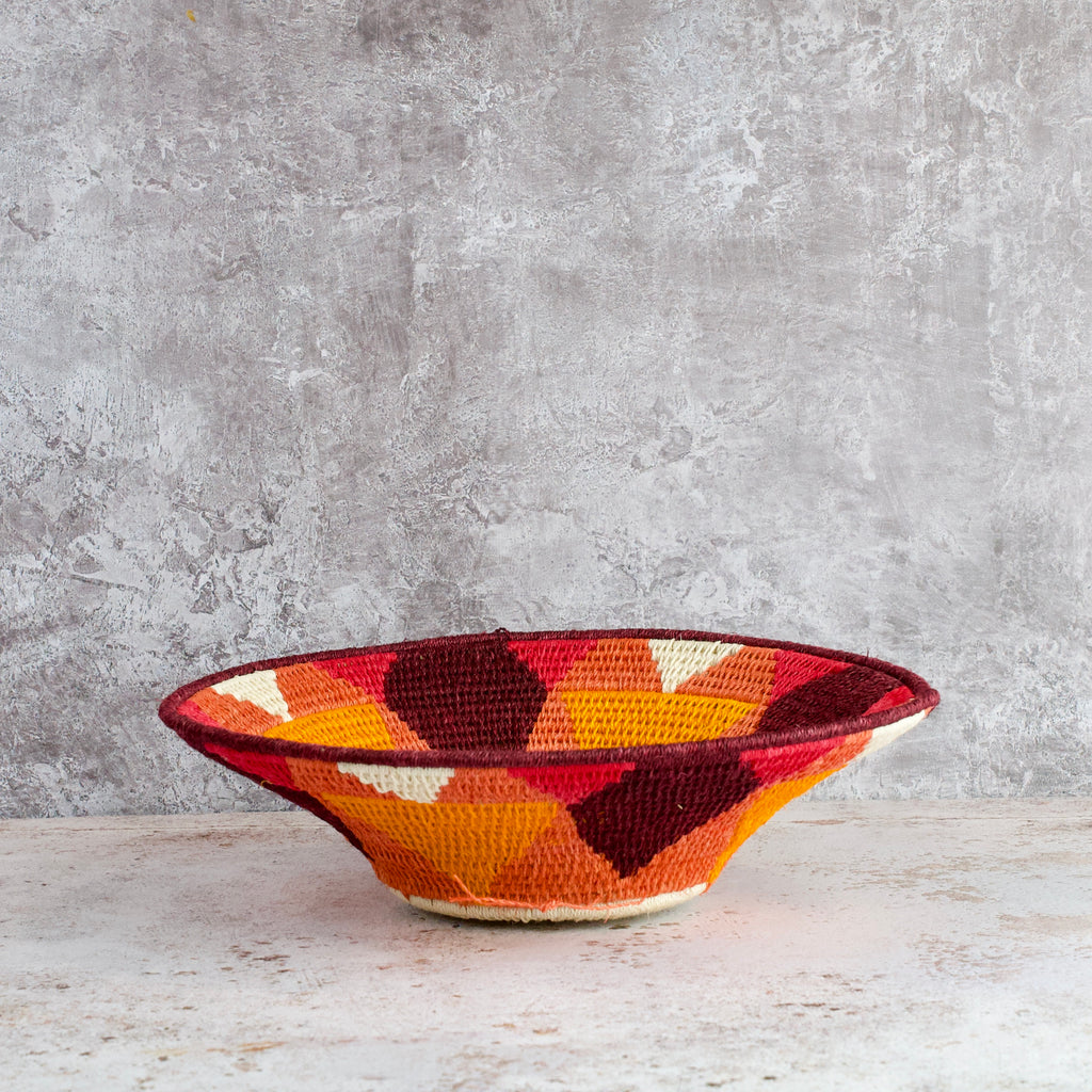 side view of medium hand woven sisal basket. sundial pattern. summer of love mixed colours of cream, mango,coral, fuscia, aubergine