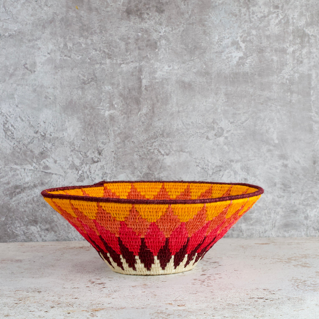 side view of a medium size hand woven sisal basket. diamond pattern. summer of love mixed colours of cream, mango,coral, fuscia, aubergine