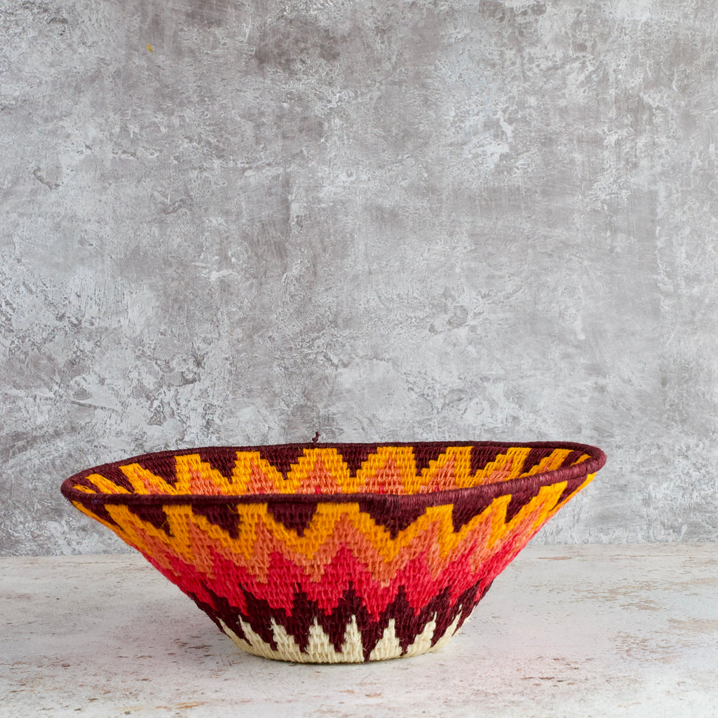 side view of medium hand woven sisal basket. Protea pattern. summer of love mixed colours of cream, mango,coral, fuscia, aubergine