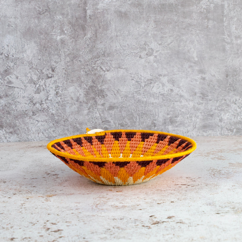 side view of a small hand woven sisal basket. diamond pattern. summer of love mixed colours of cream, mango,coral, fuscia, aubergine