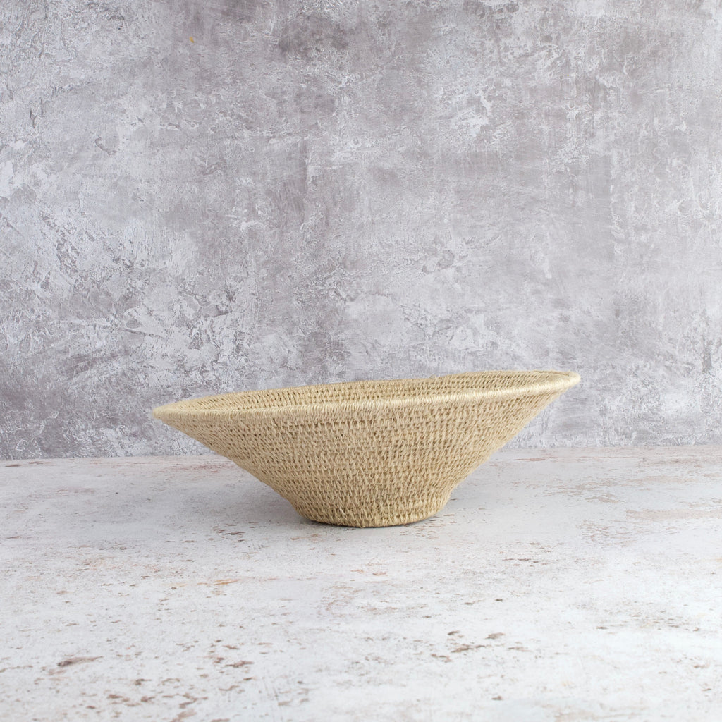 side view of medium size hand woven sisal basket in sand